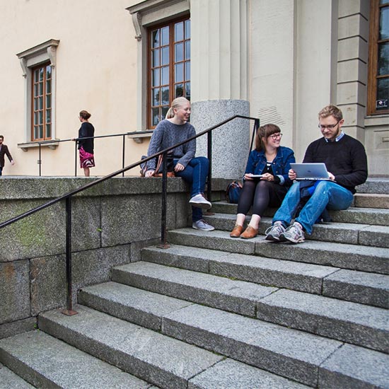 Students sitting on the stairs outside a university building